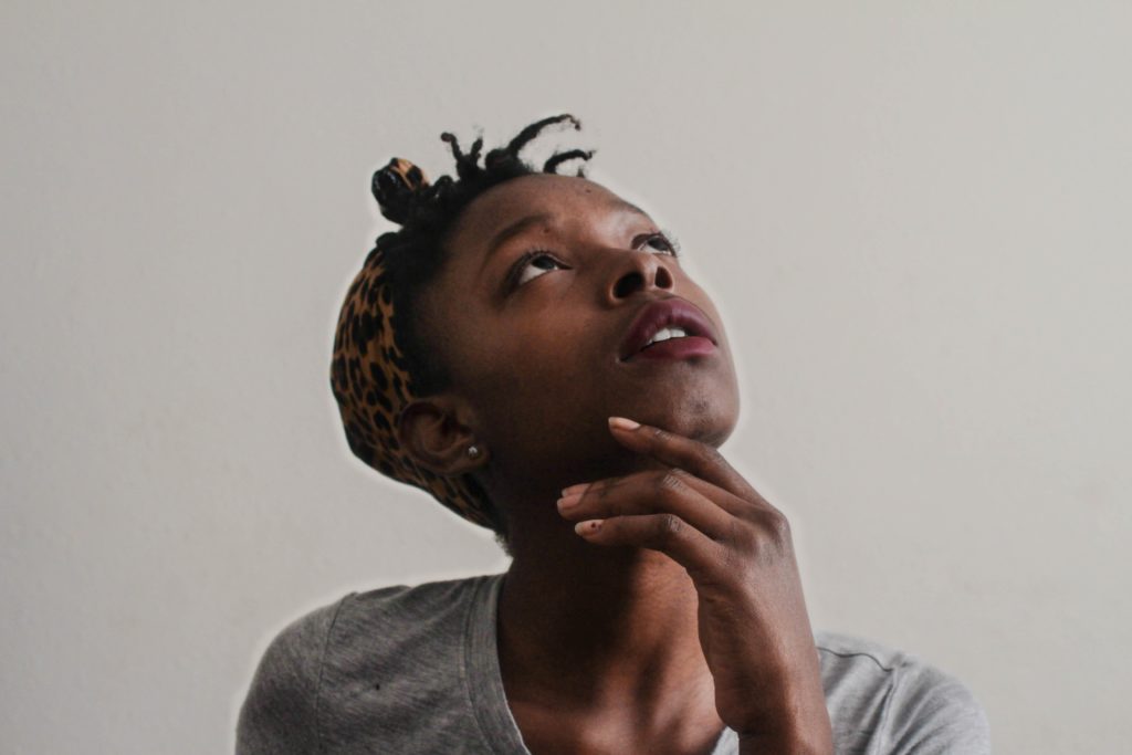 Photo by Tachina Lee on Unsplash a black woman looks up questioningly and wonders "Is my period normal?"