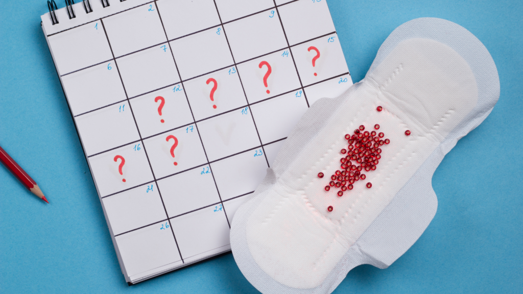 Calendar with six days marked with a red question mark and a menstrual pad with red sparkles on it against a blue backdrop