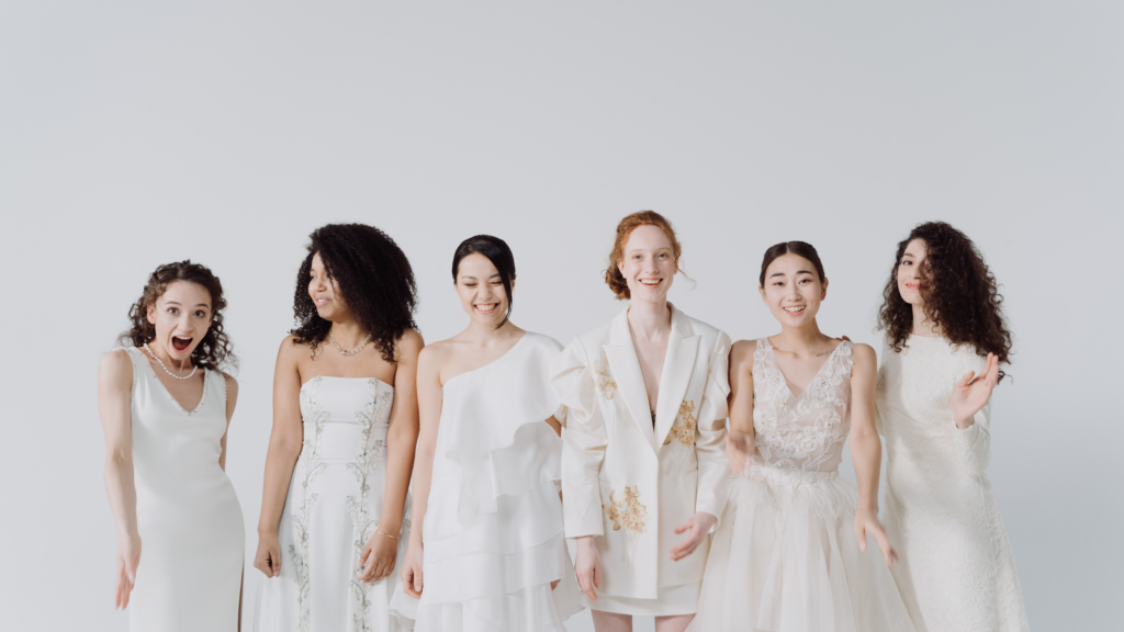 6 women of various ethnicities all wearing white dress and smiling with confidence