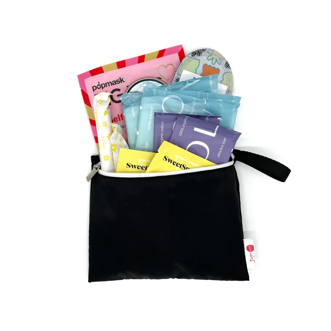 Black travel pouch full of items meant to help prepare someone for their first period including pads, pantyliners, tampons, wipes, heat patch, etc.