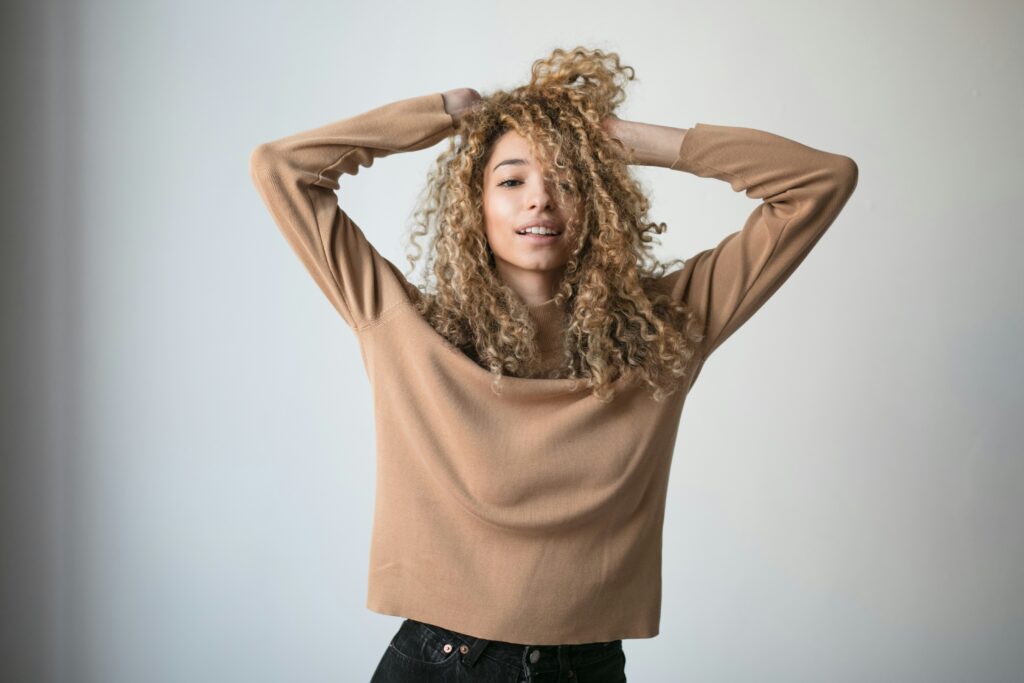 photo of woman with curly hair pushing hair up in a playful way